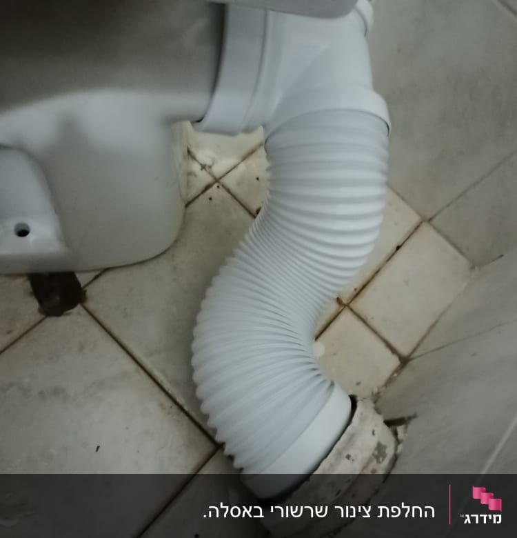 צינור גמיש מחובר לאסלה על רצפת קרמיקה
